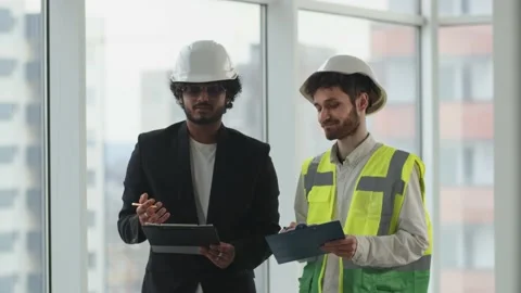 Two men in construction helmets and with paper tablets in their hands are Stock Footage 237940142