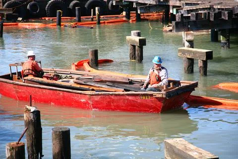 Two men with construction helmets sail in a boat in a harbour Stock Photos