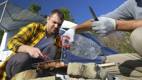 Two men cook meat on the grill near the campervans in nature Stock Footage 122088552