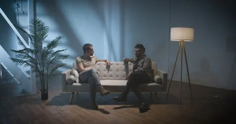 Two men on a couch interview scene, talking and sharing stories, podcast concept Stock Footage 280346341