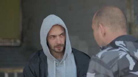 Two men of criminal appearance are talking standing in front of an abandoned old Stock Footage 153671263