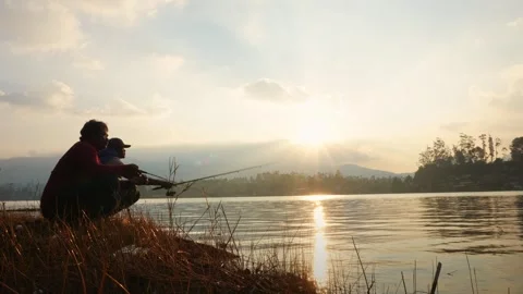 Two Men Crouch On The Lake Shore Throwing Fishing Rods Into The Lake Video stock 315770107