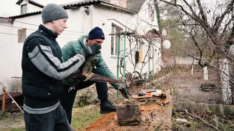Two Men Cutting Wooden Log with Hand Saw in Backyard for Firewood Stock Footage 341465330