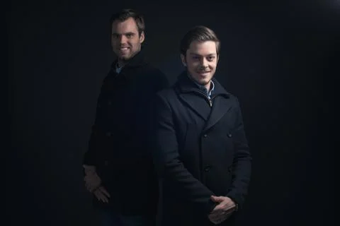 Two men in dark blue winter coat. Stock Photos