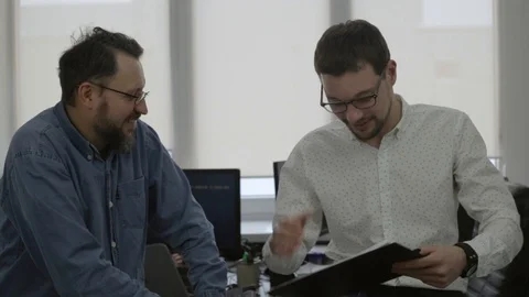 Two men dicuss something in the office Stock Footage 97351868