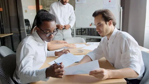 Two men discuss financial charts in an office meeting to plan future strategies 스톡 동영상 335733119