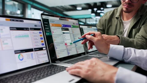 Two Men Discussing ERP Software Solutions On Laptops Stock Footage 347903372