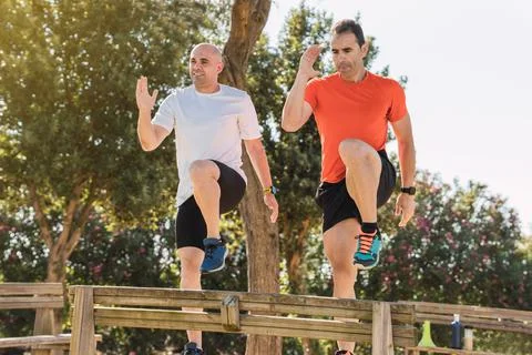 Two men doing steps on a park bench Stock Photos