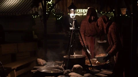 Two men dressed in robes serving food on street from outdoor cooking pot 動画素材 101198295