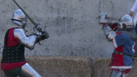 Two men dressing medieval metal armor fight a sword-fired duel. Slow motion. Video stock 76247622