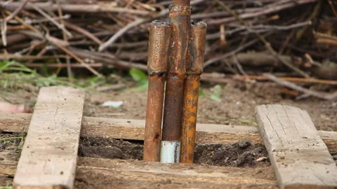 Two men drilling a well using a homemade hand-held drilling apparatus Stock Footage 265200233
