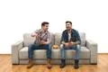 The two men drink a beer with chips on the sofa on a white wall background Photo