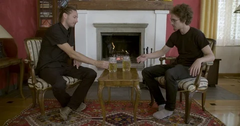 Two men drinking beer in front of the fireplace Stockbeeldmateriaal 99739394