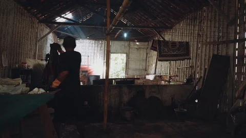 Two men dyeing walking in dark shed with batik fabric Stock Footage 90091060
