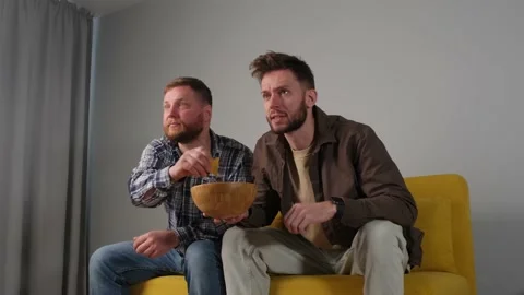 Two men eat chips and watch football Vidéo 171458121