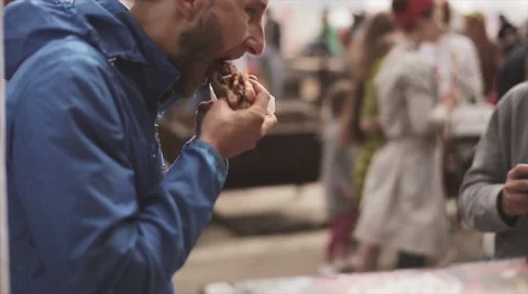 Two men eating hamburger on summer festival. Windy day. Street fast food Stock Footage 62824412
