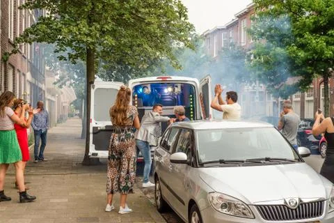 Two men elbow bump outside a social distancing street party van in Holland Stock Photos