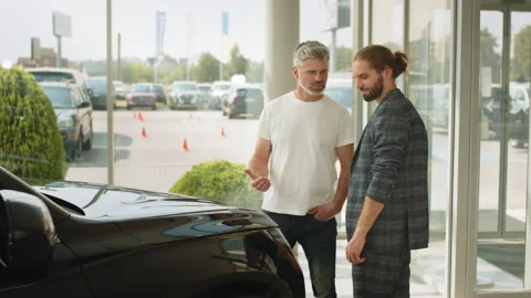 Two men elderly father and adult son in a showroom choose a new car. Young Stock Footage 240553447