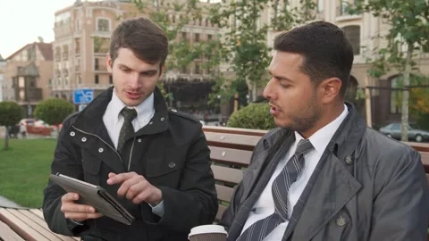 Two men engage in a focused discussion while reviewing a tablet Stock Footage 311941138