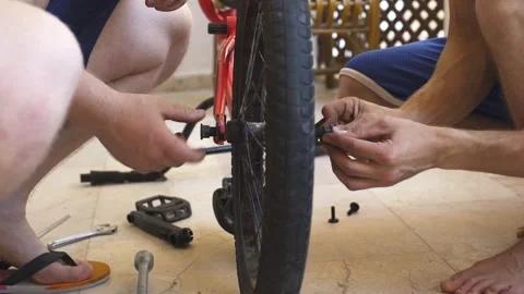 Two men engaged in bicycle maintenance, focusing on pedal installation Stock-Footage 319294011