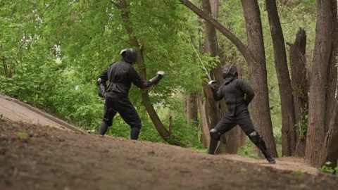 Two Men Engaged in Sword Fight on Forest Path with martial arts fencing Stock Footage 345087289