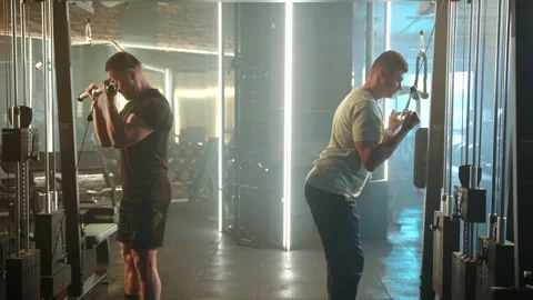 Two Men Engaging in Intensive Bicep Curl Exercises for Strength Building Stock Footage 273858988