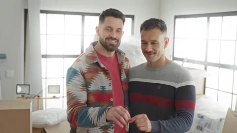 Two men exchange keys with smiling faces amid moving boxes inside an apartm.. 스톡 동영상 339217815