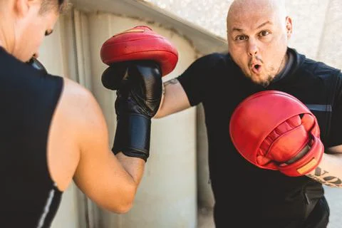 Two men exercising and fighting in outside. Boxer in gloves is training with a Stock Photos