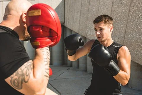 Two men exercising and fighting in outside. Boxer in gloves is training with a Stock Photos
