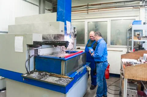 Two men in factory at eroding machine 스톡 사진