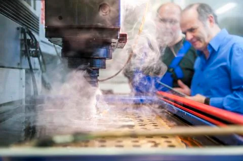 Two men in factory at eroding machine Foto stock