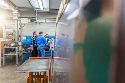 Two men in factory talking at eroding machine Foto stock