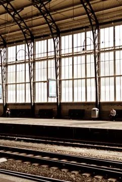 Two men far from each other at empty train station with stained big window be Stock Photos