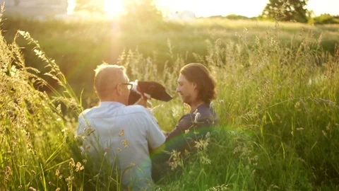 Two men, father and son are resting sitting in the grass on the shore of the Stock Footage 90744980