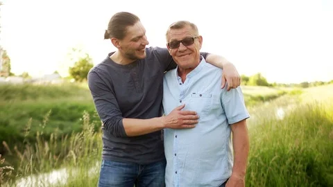 Two men, father and son, talking with each other embracing. A young man points Stock Footage 90841994