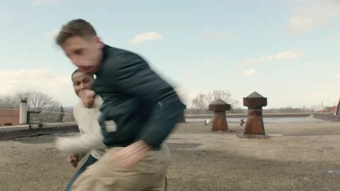 Two men fight on a warehouse rooftop with skilled kicks and punches in overcast Stock-Footage 199460807