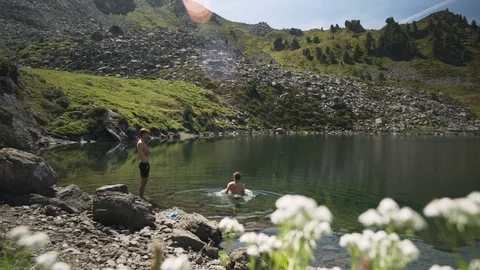 Two men friends jumping into mountain lake, 4K Stock Footage 129613541