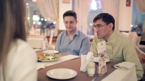 Two men with girl sitting at a table in a restaurant. Stock Footage 56698183