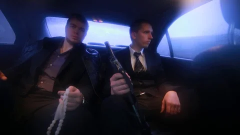Two men going in car. One of them holds a a rosary, the other holding a shotgun 스톡 동영상 129420284