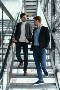 Two men going up, down stairs while chatting Stock Photos
