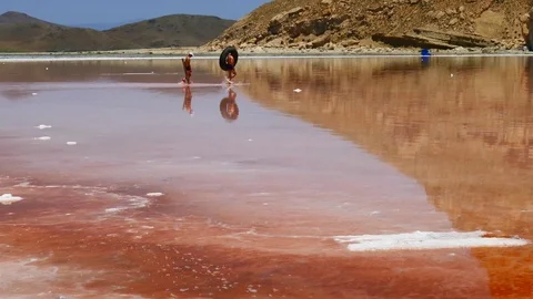 Two men going to swim in a red pink sea with a tube in a surrealistic atmosphere Stock Footage 70355649