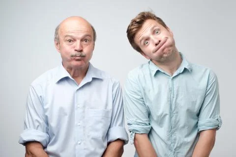 Two men grimacing, inflating cheeks, holding breath Foto stock