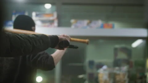 Two men with a gun and baseball bat threatening a person at the cash register Stock Footage 275598948