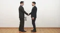 The two men handshake and exchange suitcases on a white wall background 4k or 4k+ Resolution