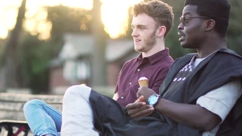 Two men happy friends talking eating ice cream sunset sitting laugh pair guys Vídeo Stock 74295212