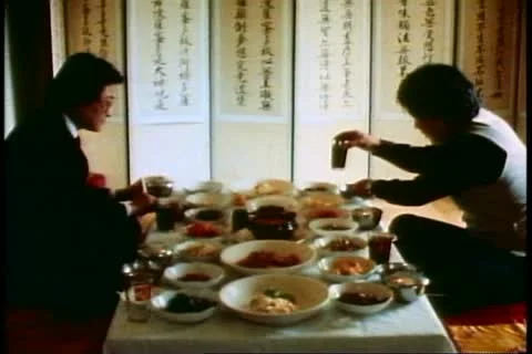 Two men have a traditional Korean lunch at low table using chopsticks, Stock Footage