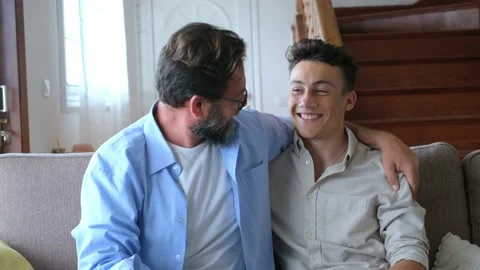 Two men having fun together on the sofa enjoying home lifestyle and laughing loo Stock Footage 171898203