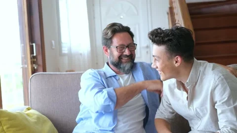 Two men having fun together on the sofa enjoying home lifestyle and laughing for Stock Footage 171898713