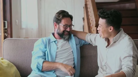 Two men having fun together on the sofa enjoying home lifestyle and laughing for 库存影片 171901146