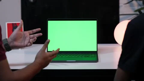 Two Men Having a Video Call on a Laptop with a Green Screen in a Dimly Lit A Video stock 294875331